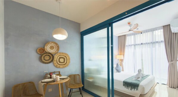 A hotel room with a dining area, a bed with a view, and a ceiling fan. - The Shore Kota Kinabalu Borneo Grand Roam Suites (Kota Kinabalu)