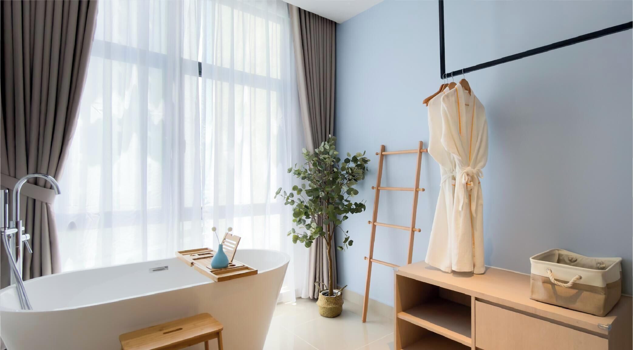 A modern bathroom with a bathtub, a wooden vanity, a plant, and a robe hanging on a rack.
