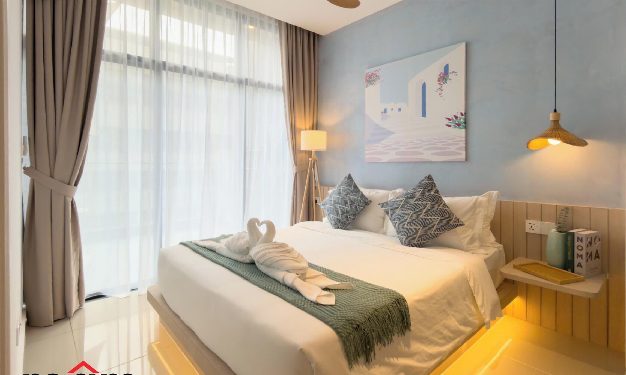 A hotel room with a bed, curtains, a lamp, a painting, and a bedside table.