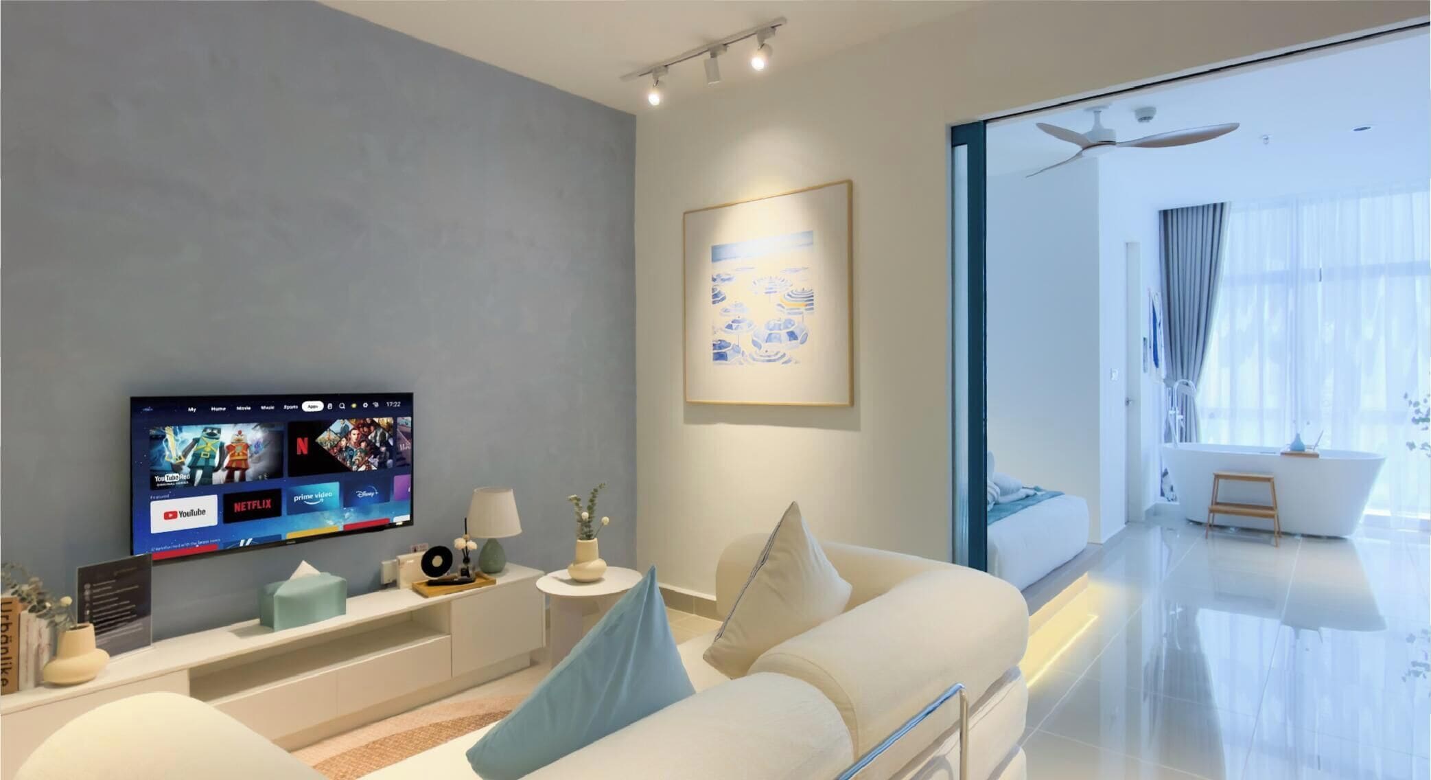 A modern living room with a flat-screen TV, a sofa, a side table, and a large window.