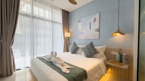 Quarto de hotel com cama, luminária, pintura e mesa de cabeceira com um vaso e uma caixa.