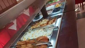 Un bufé con diversos alimentos, incluyendo salchichas, panqueques y otros productos para el desayuno.