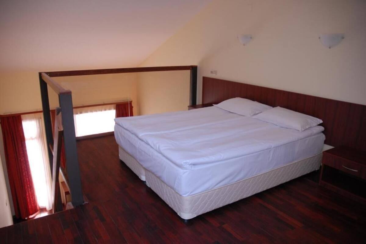 A bedroom with a wooden bed, a nightstand, and a window with curtains.