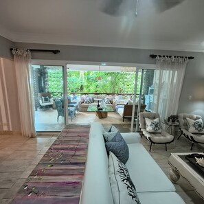 Ein großzügiger Wohnbereich mit Sofa, Sesseln, Couchtisch und Blick auf die Terrasse.