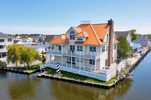 Ein Haus am Wasser mit einem markanten Schornstein, mehreren Balkonen und einer anlegenden Mole.
