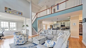Ein geräumiges Wohnzimmer mit einem großen Ecksofa, einem Couchtisch und einer Treppe, die zu einer oberen Ebene führt.
