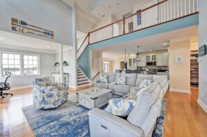 Ein geräumiges Wohnzimmer mit einem großen Ecksofa, einem Couchtisch und einer Treppe, die zu einer oberen Ebene führt.
