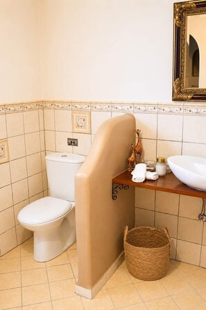 Kylpyhuone, jossa on wc, pesuallas, peili ja koristeellinen kirahvihahmo.