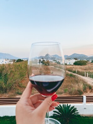 A hand holding a wine glass with a view of a mountainous landscape in the background.