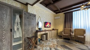 A room with a wooden wardrobe, a mirror, a desk with a computer, a sofa, and a patterned rug. - Tengealti Resort Hotel (Quba)