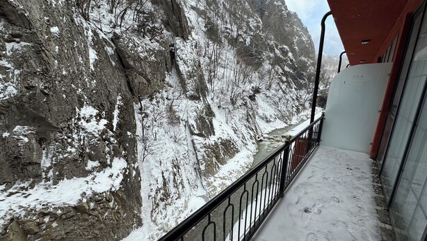 A balcony with a view of a snow-covered mountain and a rocky cliff. - Tengealti Resort Hotel (Quba)