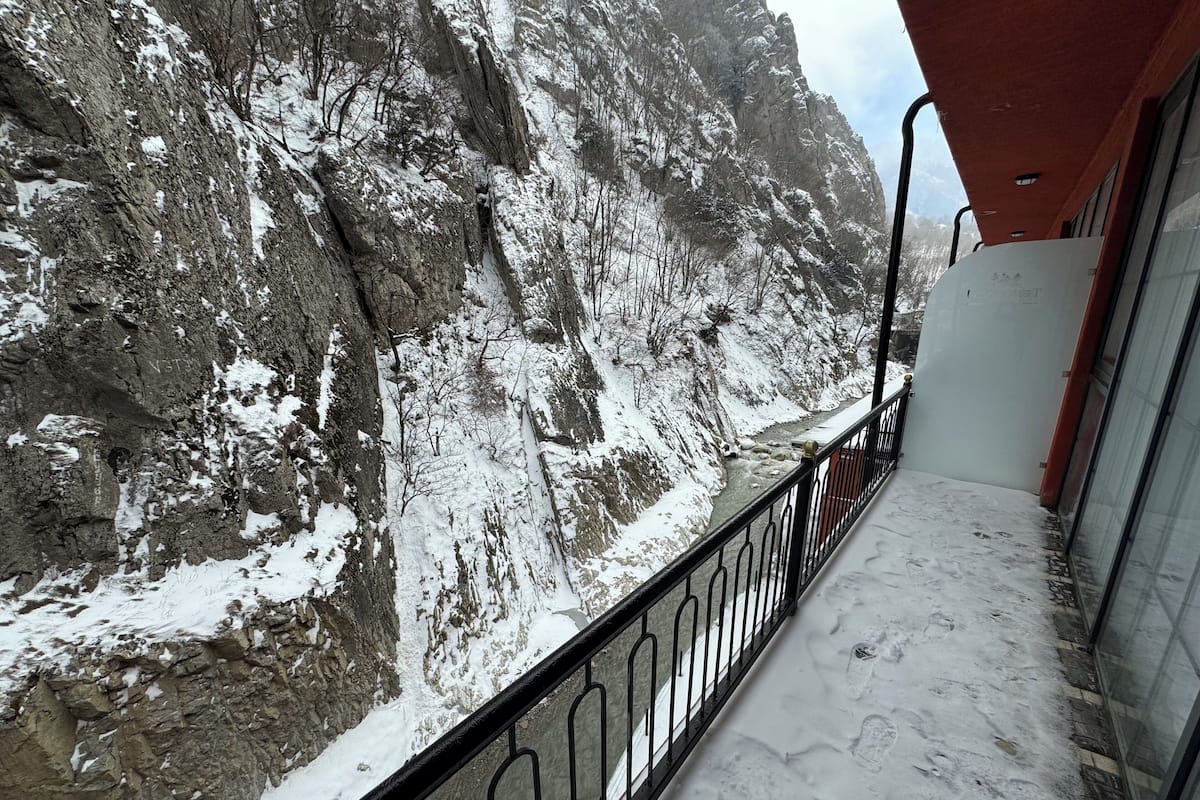 A balcony with a view of a snow-covered mountain and a rocky cliff.
