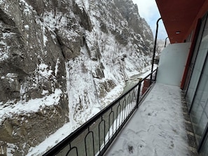 A balcony with a view of a snow-covered mountain and a rocky cliff.
