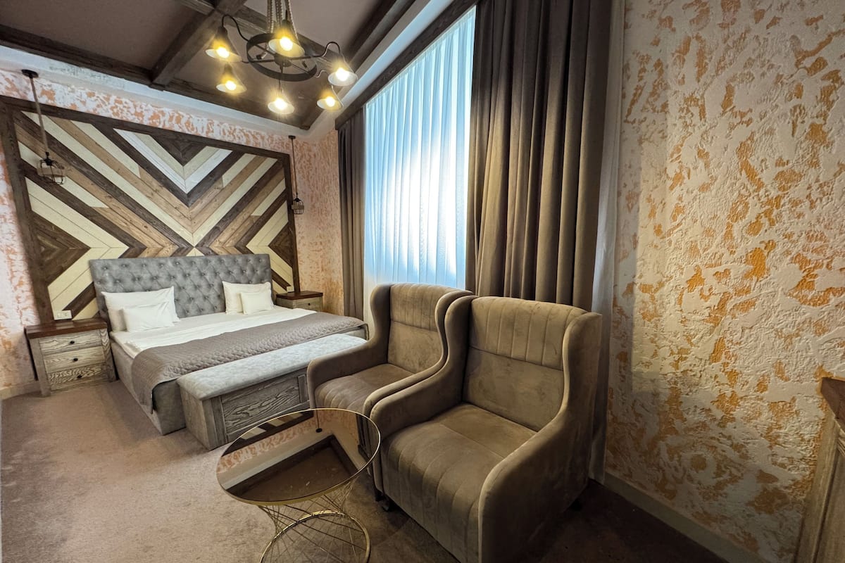 A bedroom with a bed, a chair, a unique wall design, and a ceiling light fixture.