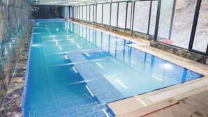 An indoor swimming pool with clear water, tiled floor, and a view of the outside through large windows. - Tengealti Resort Hotel (Quba)