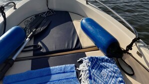 A boat's interior with a cushioned seat, a blue towel, and a paddle. - Top location on the lake - Charming yellow bungalow with terrace & lake view (Neuruppin)