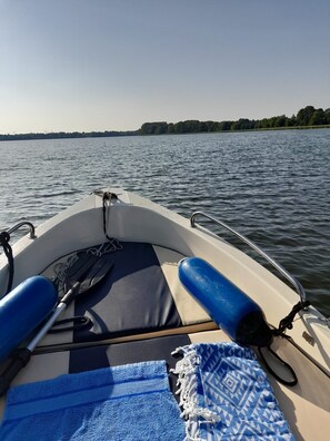 A boat's interior with a cushioned seat, a blue towel, and a paddle. - Top location on the lake - Charming yellow bungalow with terrace & lake view (Neuruppin)