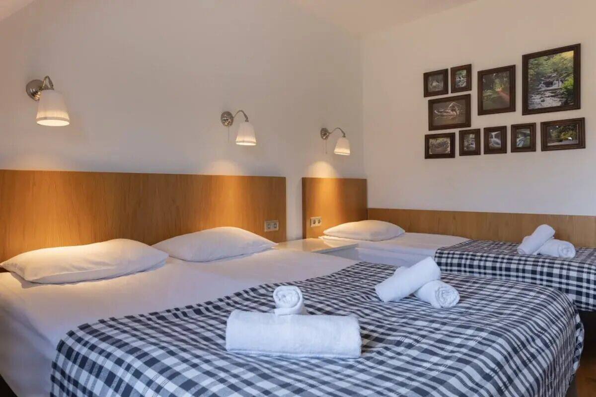 Une chambre d’hôtel avec deux lits, chacun doté d’une tête de lit, d’un luminaire fixé au mur et d’un ensemble de tableaux encadrés.