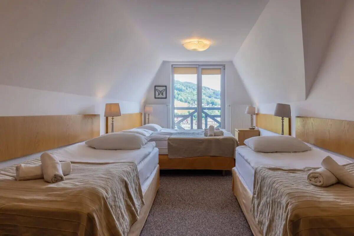 Une chambre d’hôtel avec deux lits, une fenêtre donnant sur un beau paysage et un luminaire au plafond.