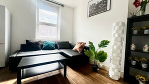 Een moderne woonkamer met een bank, een salontafel, een potplant, een witte bakstenen muur en een ingelijste foto.
