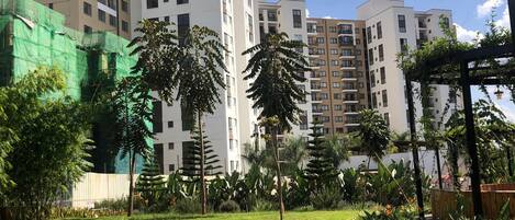 A residential area with multi-story buildings, a grassy lawn, and some trees.