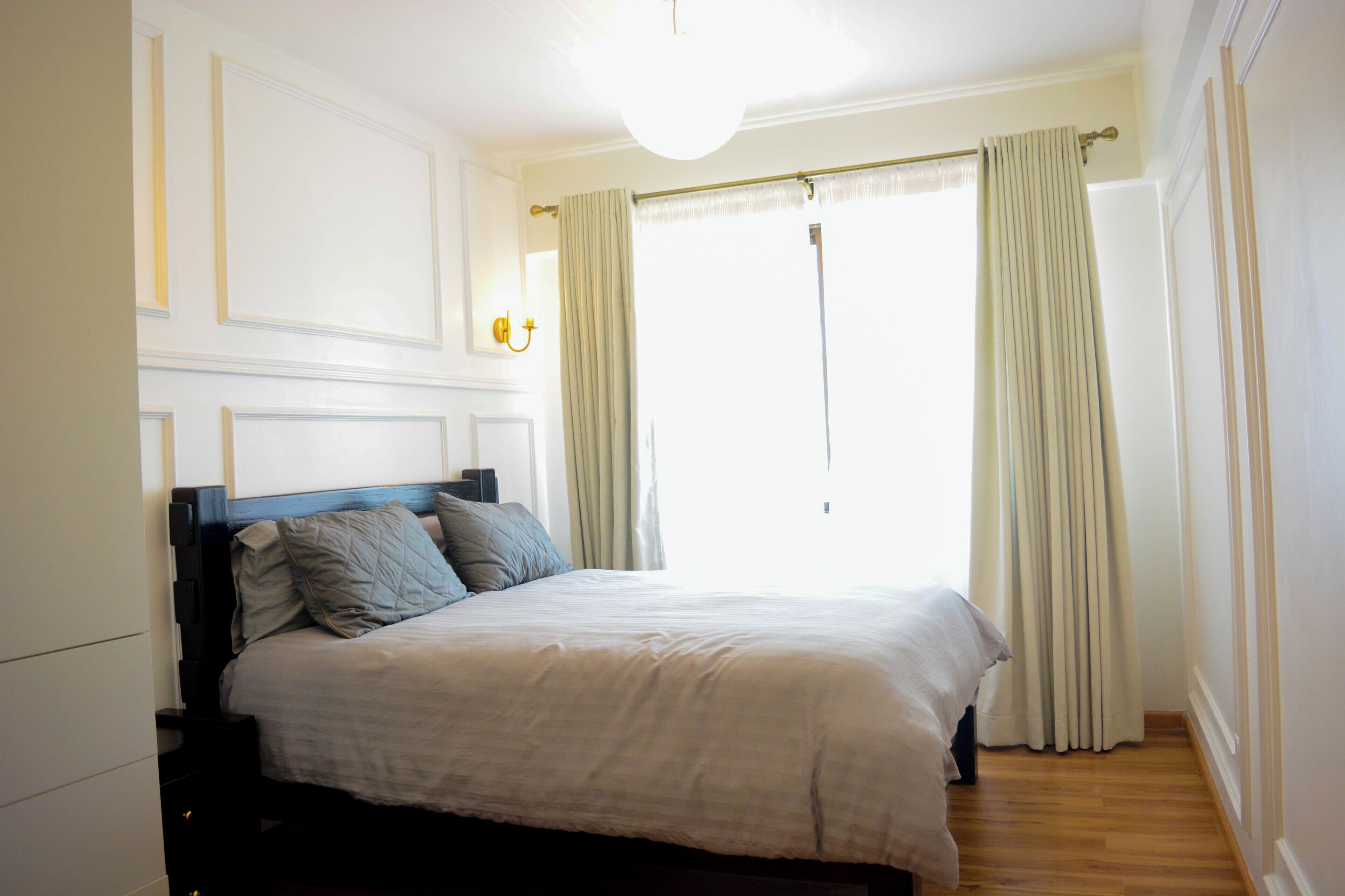 A bedroom with a bed, curtains, and a light fixture.