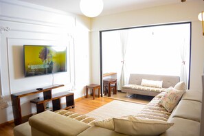 Una sala de estar con televisor, sofá y vistas amplias por un gran ventanal.