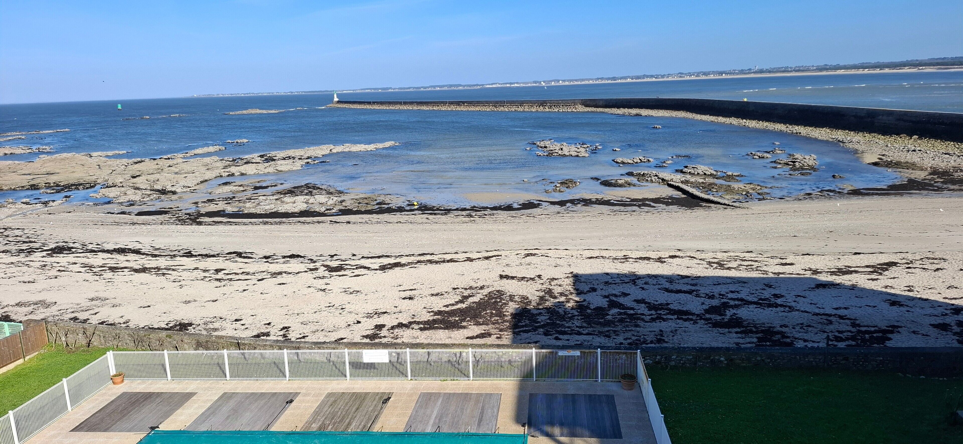 Une plage au paysage rocheux, avec une terrasse en bois et une vue sur la mer.