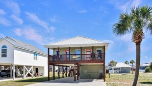 A two-story building with a covered porch, a garage, and a palm tree. - 🏖️Steps to Beach | Great Outdoor Spaces | Perfect for Families | Beach Dreams☀️ (St. Joe Beach)