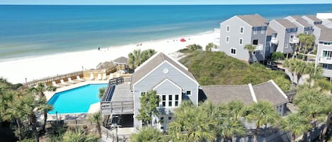 A beachfront property with a swimming pool, beach access, and multiple buildings.