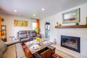A living room with a fireplace, a dining table set for four, and a sofa.