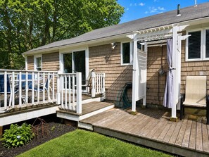 Een huis met een houten terras, een overdekte veranda en een kleine tuin.