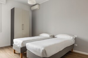 A bedroom with two single beds, a wardrobe, and an air conditioning unit. - Casa Amarenzi by Wonderful Italy (Bologna)