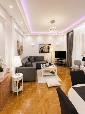 A modern living room with a sofa, coffee table, TV, and decorative items. - Urban Noir Escape Neos Kosmos Chic Stay (Athens)