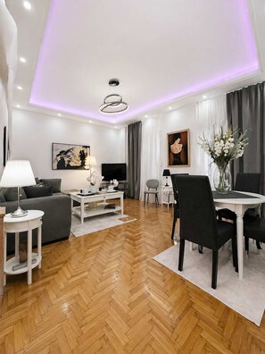 A modern living room with a sofa, TV, and dining area. - Urban Noir Escape Neos Kosmos Chic Stay (Athens)