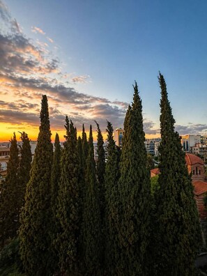 A cityscape with tall cypress trees and buildings in the background. - Urban Noir Escape Neos Kosmos Chic Stay (Athens)