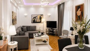 Een moderne woonkamer met een bank, salontafel, televisie en een eetgedeelte met stoelen en een tafel.