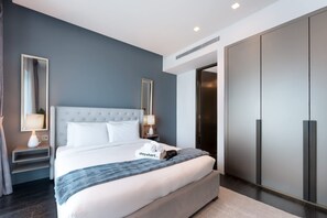 Ein modernes Hotelzimmer mit einem großen Bett, einem Kleiderschrank und einem Nachttisch mit einer Lampe.