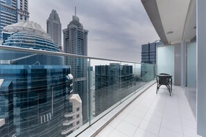 Quarto de hotel moderno com varanda, janelas amplas e vista para a paisagem urbana.
