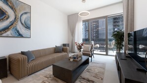 A modern living room with a sofa, coffee table, and a large abstract painting. - Free Housekeeping Visits During Your Stay - Stayshort - Stunning 1 Bed in Maritime City That Sleeps 2 (Dubai)