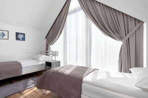 A bedroom with two beds, a nightstand, a lamp, and a window with curtains. - Two-level Apartment | Garden | Parking | Close to the Beach (Jastrzębia Góra)