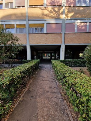 Un bâtiment doté d’une galerie couverte, d’une végétation de part et d’autre, et d’une façade en briques.