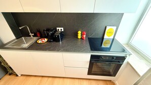 Een moderne keuken met een zwart aanrecht, een koffieapparaat, een broodrooster en een afwasschaal.