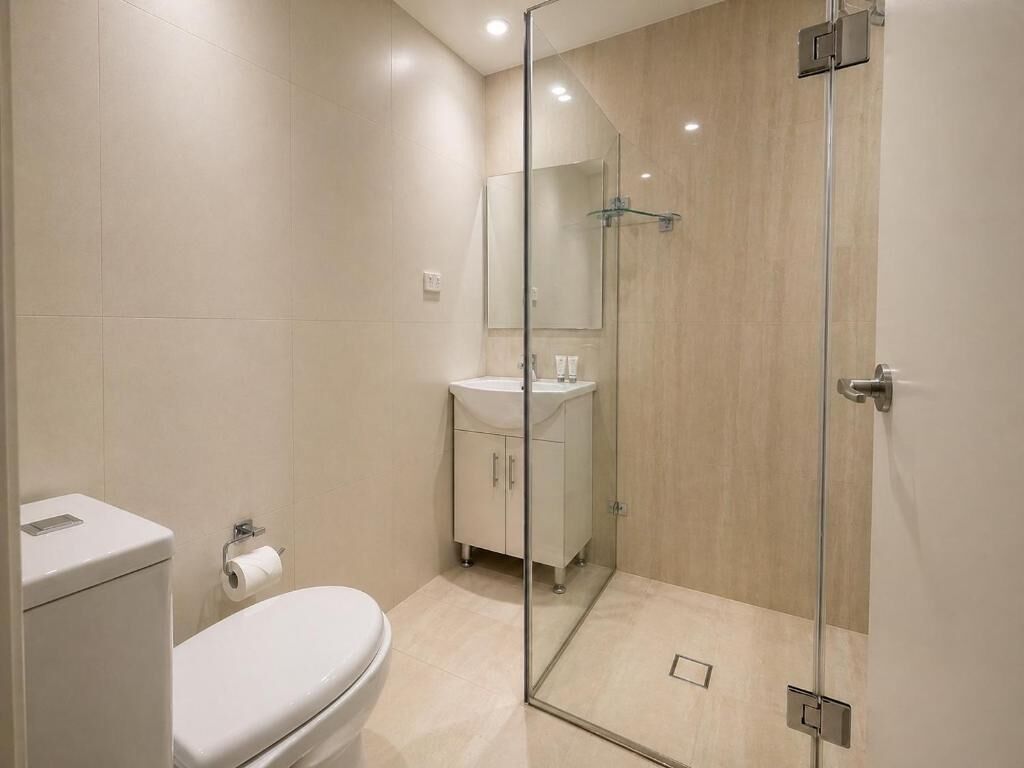 A modern bathroom with a toilet, sink, and glass shower enclosure.