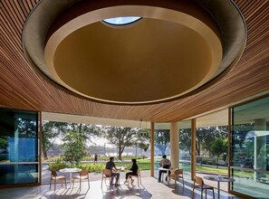 A modern interior with a circular ceiling, large windows, and outdoor seating.