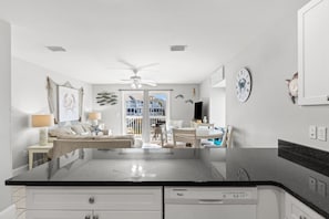 Eine moderne Küche mit schwarzem Arbeitsplatz, weißen Schränken und einem Deckenventilator.