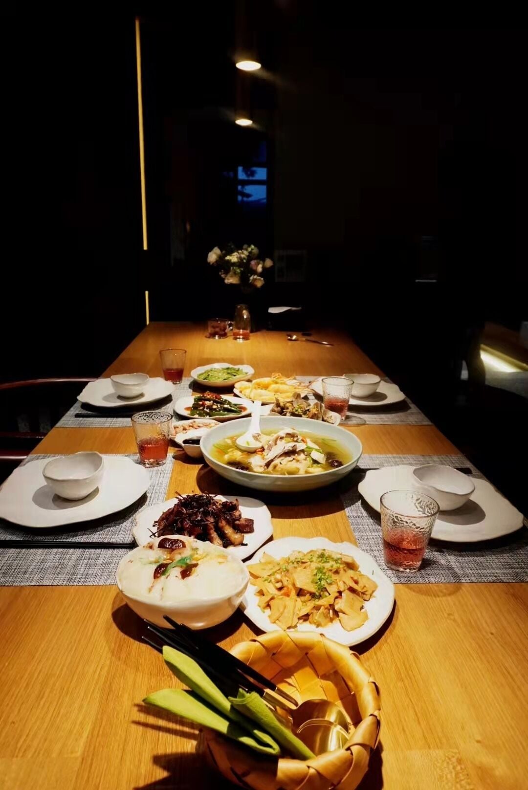 Mesa de jantar posta com diversos pratos, pauzinhos e copos.