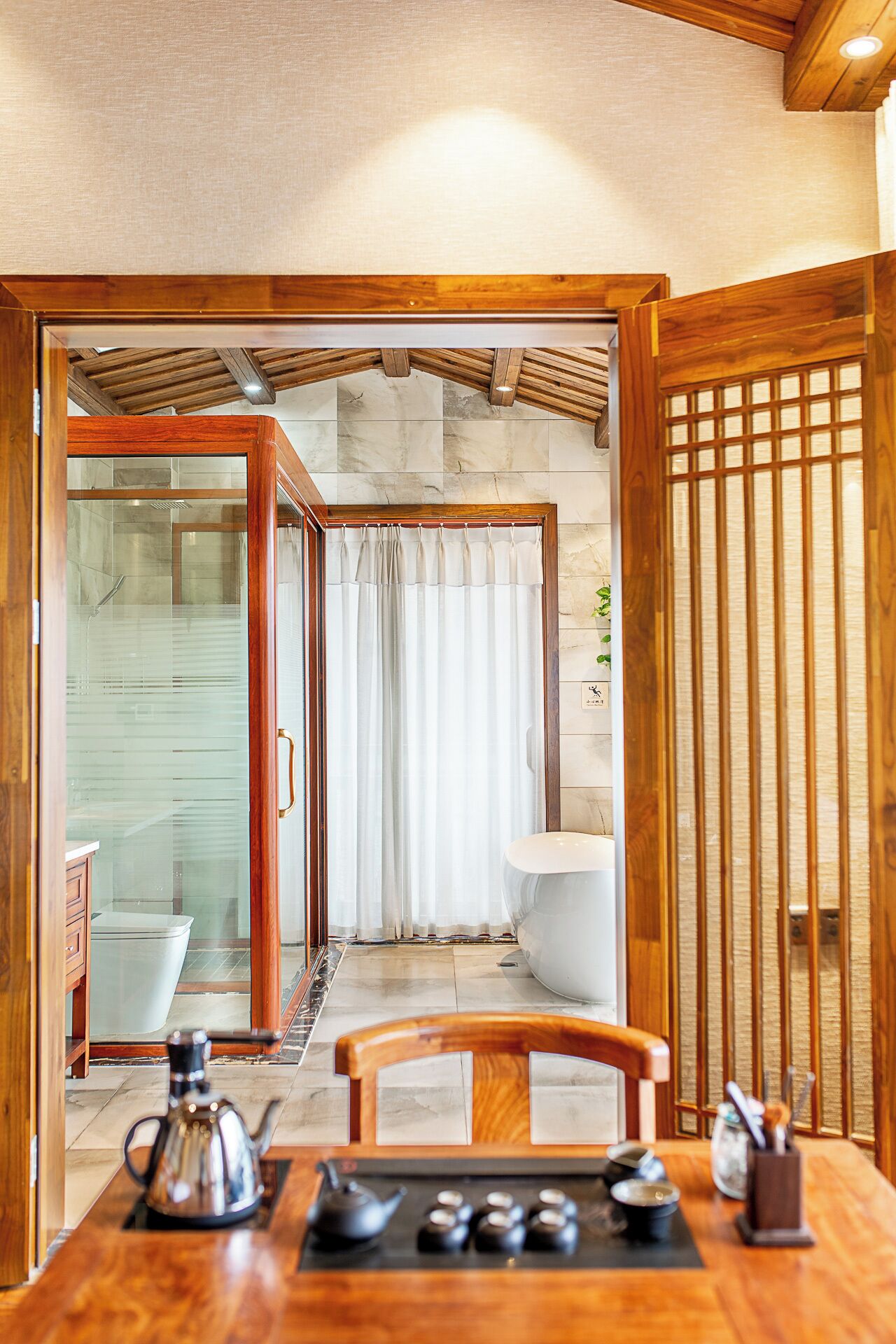 Une pièce aux murs en bois, dotée d’une porte vitrée donnant accès à une salle de bain, avec des toilettes blanches et un lavabo.