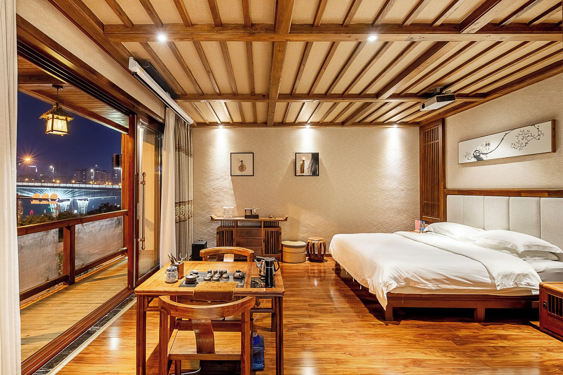 Une chambre avec un lit, une table avec un service à thé, une vue sur la ville et un balcon avec une balustrade.