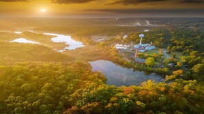 An aerial view of a forested area with a lake, a large water tower, and industrial structures.